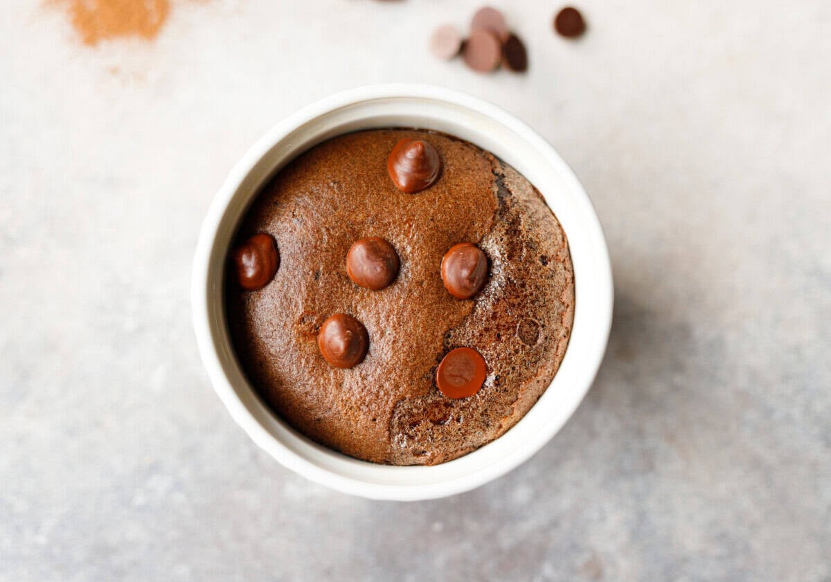Low-carb chocolate collagen mug cake in a white ramekin with chocolate chips on top