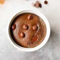 Low-carb chocolate collagen mug cake in a white ramekin with chocolate chips on top