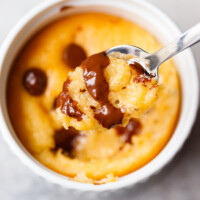 Freshly baked single serve protein cake in a white ramekin with golden top and melted chocolate chips.