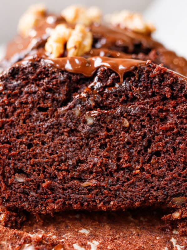 Vegan chocolate walnut loaf cake slice showing moist chocolate crumb and glaze
