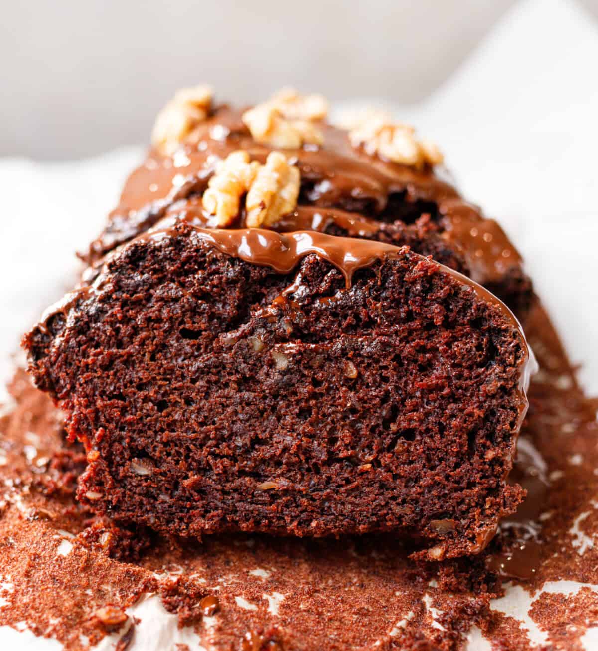 Vegan chocolate walnut loaf cake sliced with chocolate glaze and walnuts