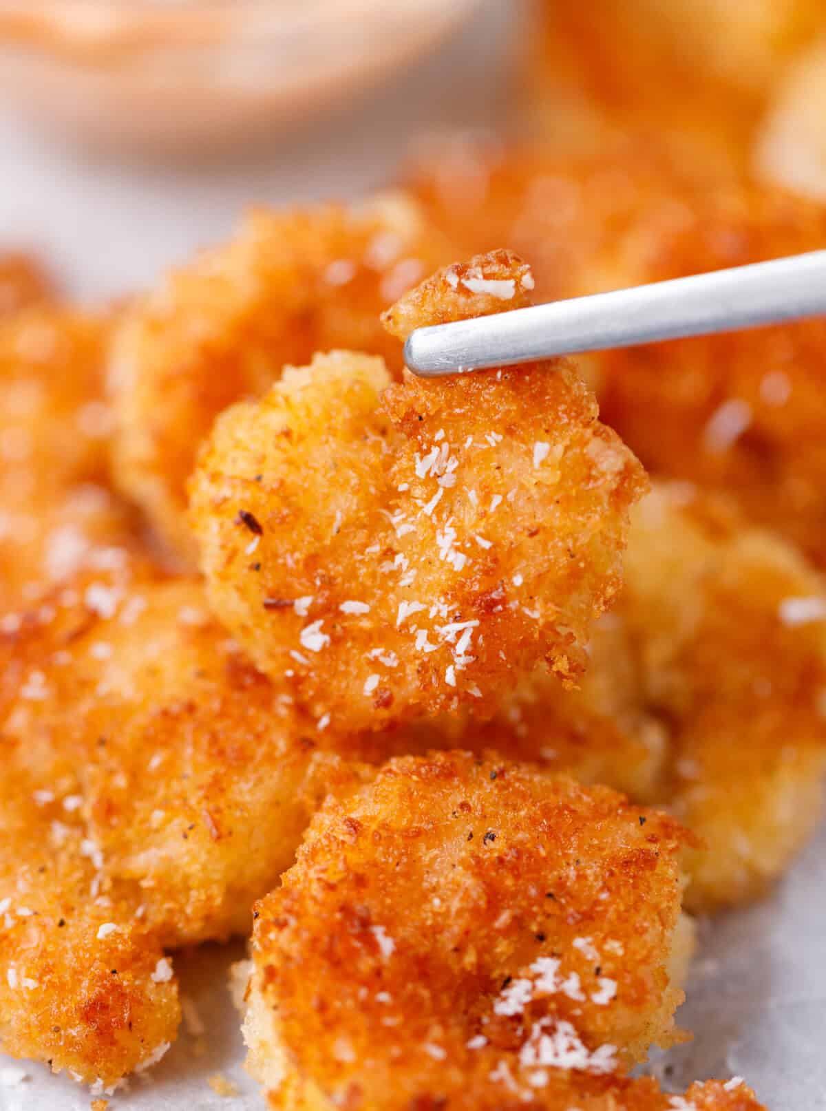 Crispy coconut shrimp held on a fork showing golden crunchy coating