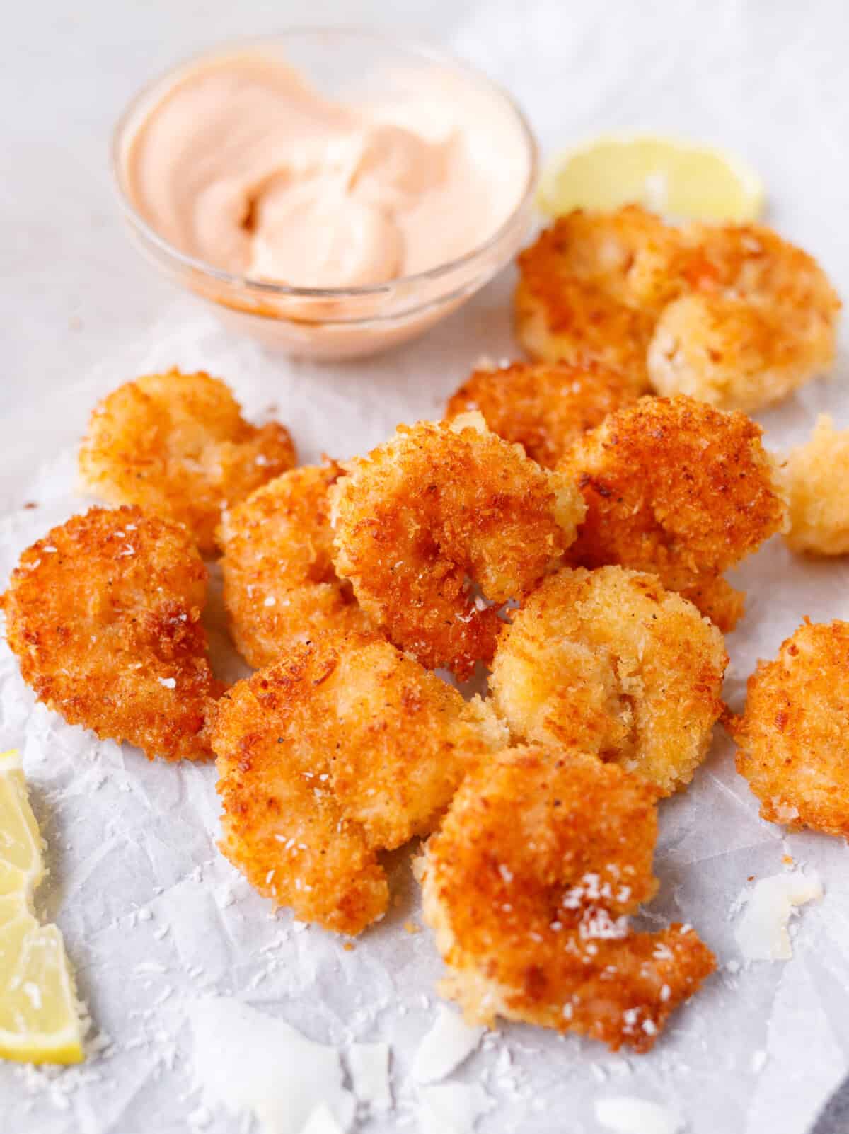 Crispy coconut shrimp served with dipping sauce and lemon wedges