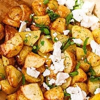 Air fryer roasted baby potatoes in a wooden bowl with crumbled feta, dill, parsley, and green onion just added