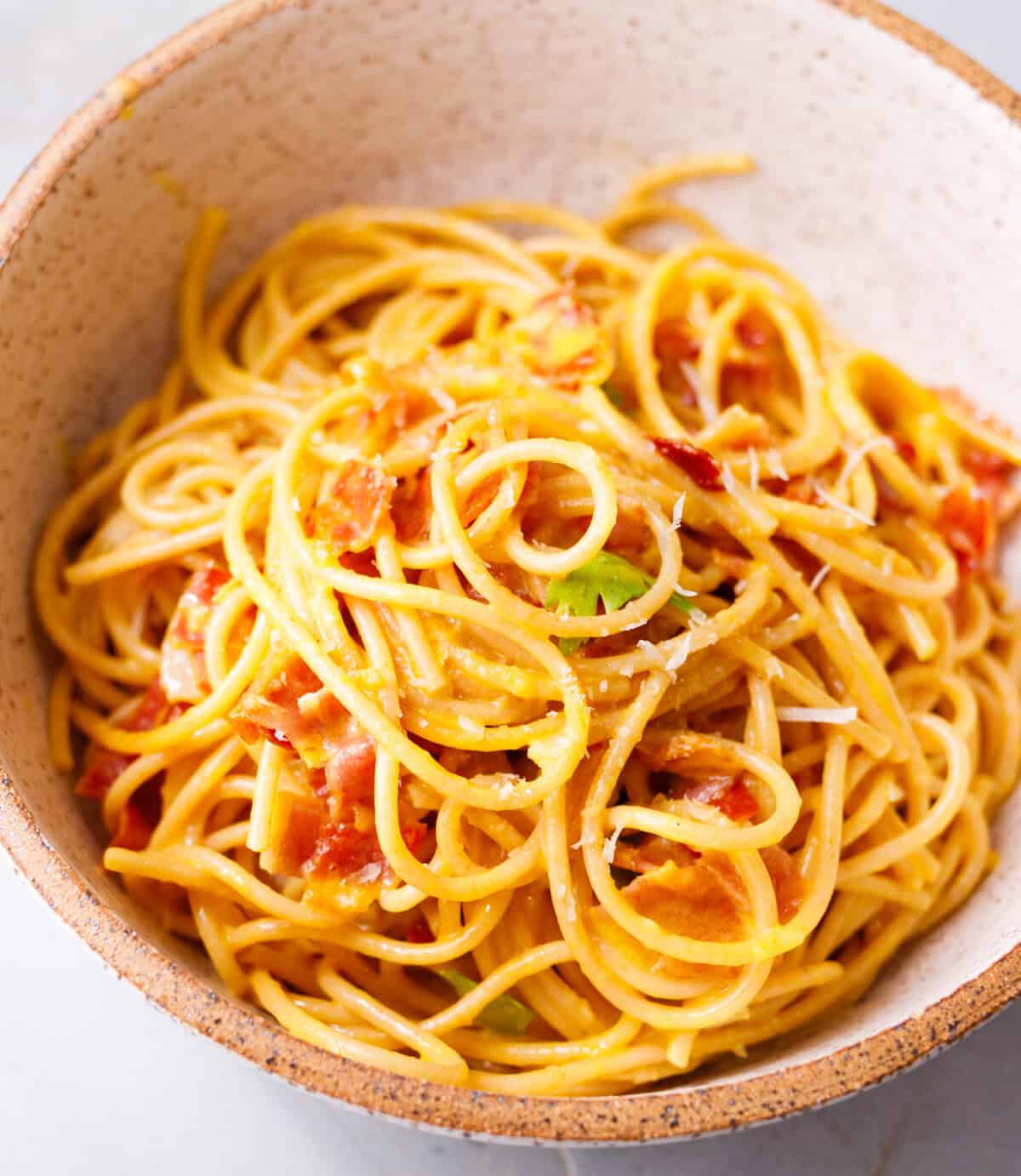 Bowl of 20 minute pasta carbonara with spaghetti, bacon, Parmesan, and parsley.