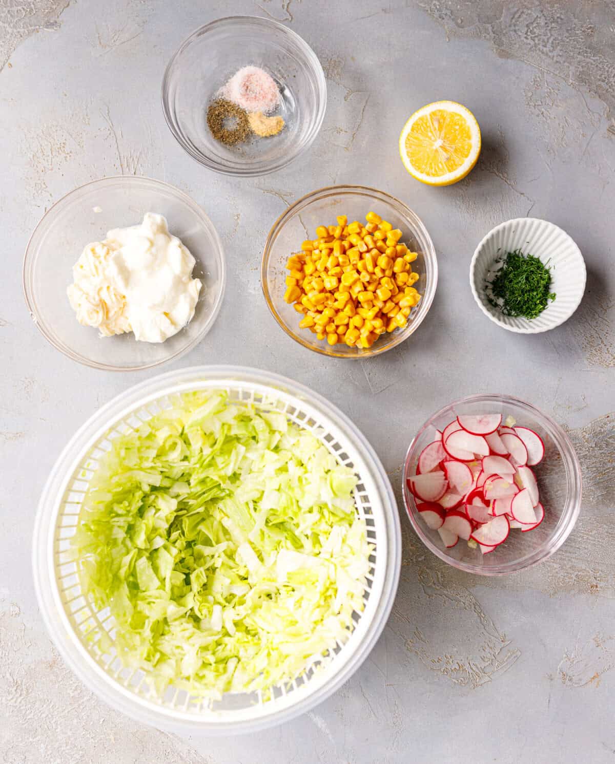  Ingredients for iceberg lettuce salad including chopped lettuce, corn, radishes, yogurt, mayo, lemon, and fresh dill