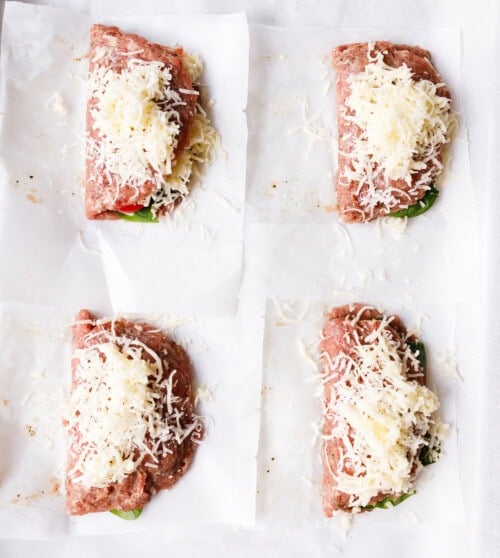our folded ground turkey pockets topped with shredded mozzarella on parchment-lined baking sheet ready to bake