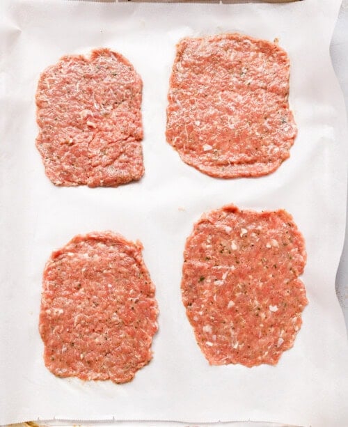 our seasoned ground turkey portions pressed into thin flat ovals on parchment paper ready to be filled