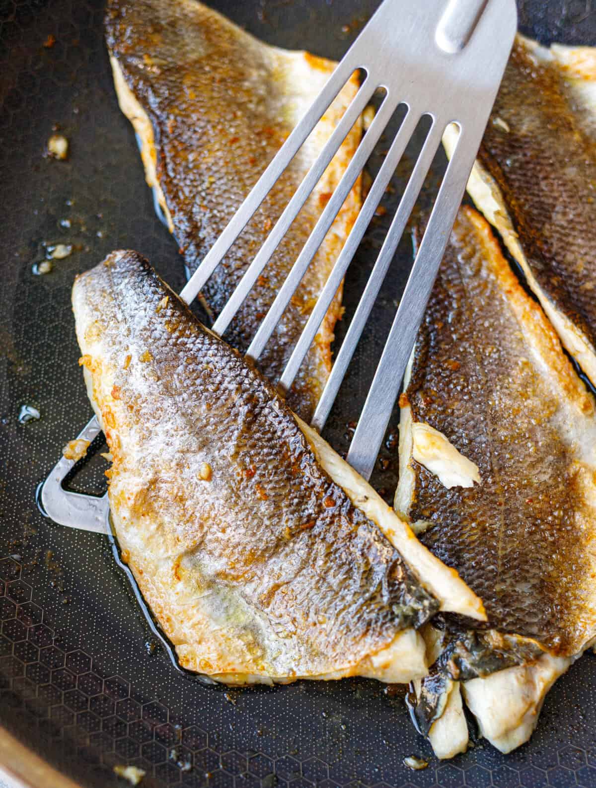 Flipping a crispy-skin branzino fillet with a fish spatula