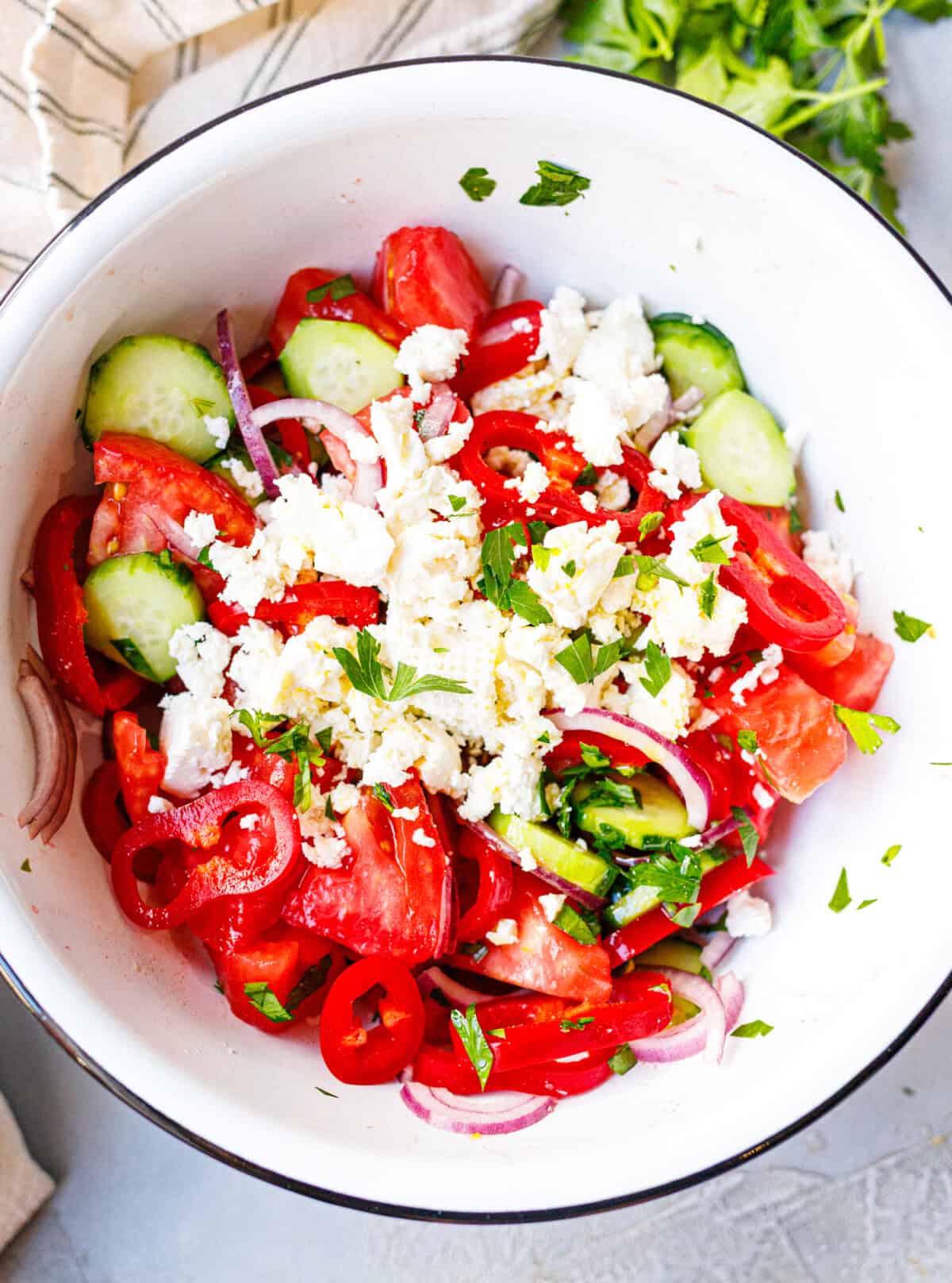 Shopska salad topped with crumbled sirene cheese and a drizzle of olive oil