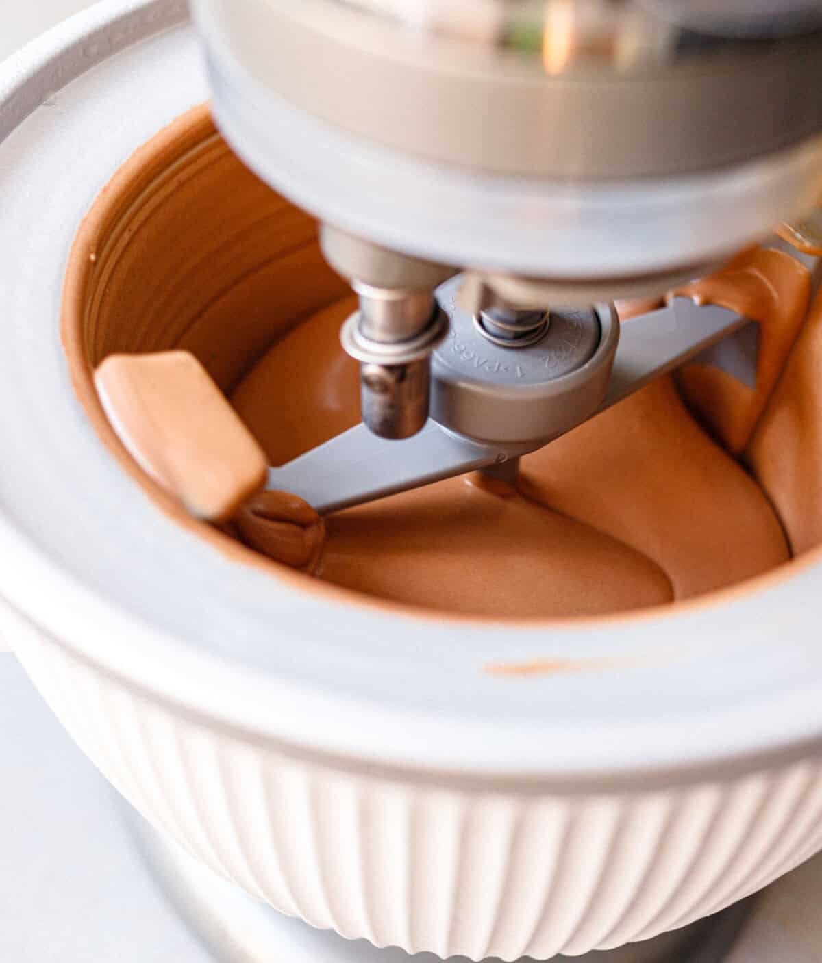 Chocolate condensed milk ice cream churning in an ice cream maker until thick and creamy