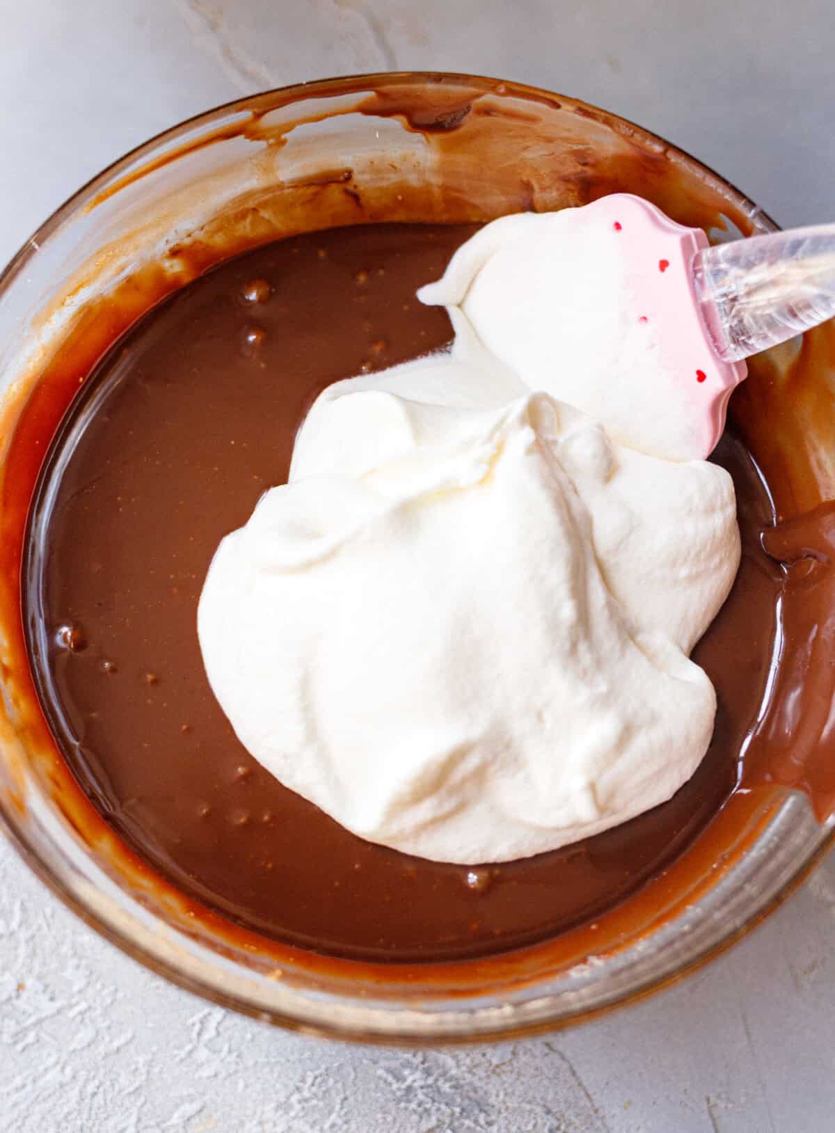 Whipped cream being folded into melted chocolate for no-churn chocolate ice cream