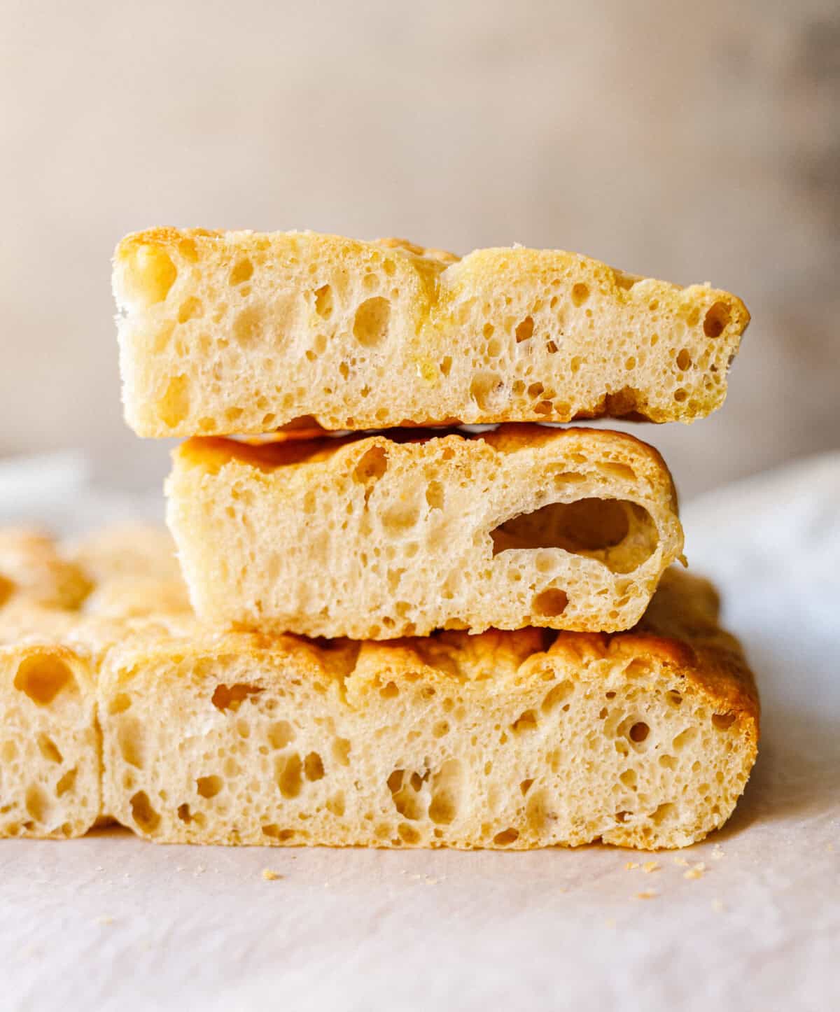 Stacked pieces of homemade focaccia showing the airy, bubbly crumb inside