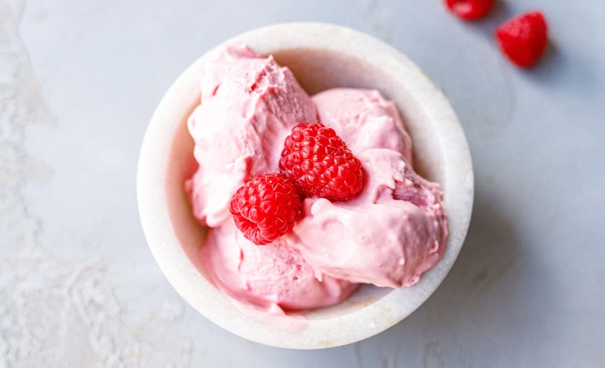 Overhead bowl of low-carb raspberry mascarpone ice cream garnished with fresh raspberries