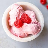 Bowl of low-carb raspberry mascarpone ice cream topped with two fresh raspberries