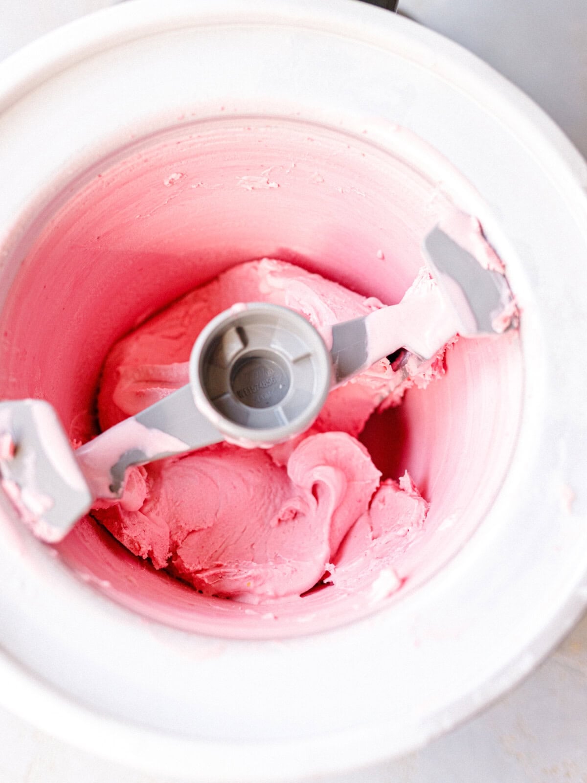Freshly churned raspberry mascarpone ice cream with a soft-serve texture in the machine