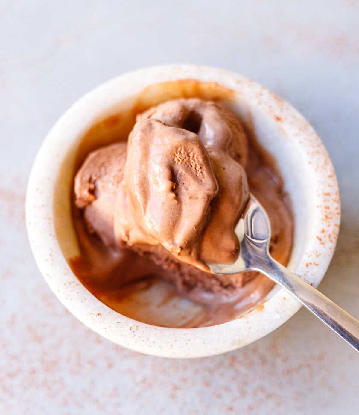 Bowl of chocolate condensed milk ice cream with a spoon, starting to melt