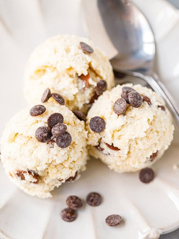 Three scoops of cottage cheese cookie dough topped with chocolate chips on a scalloped plate