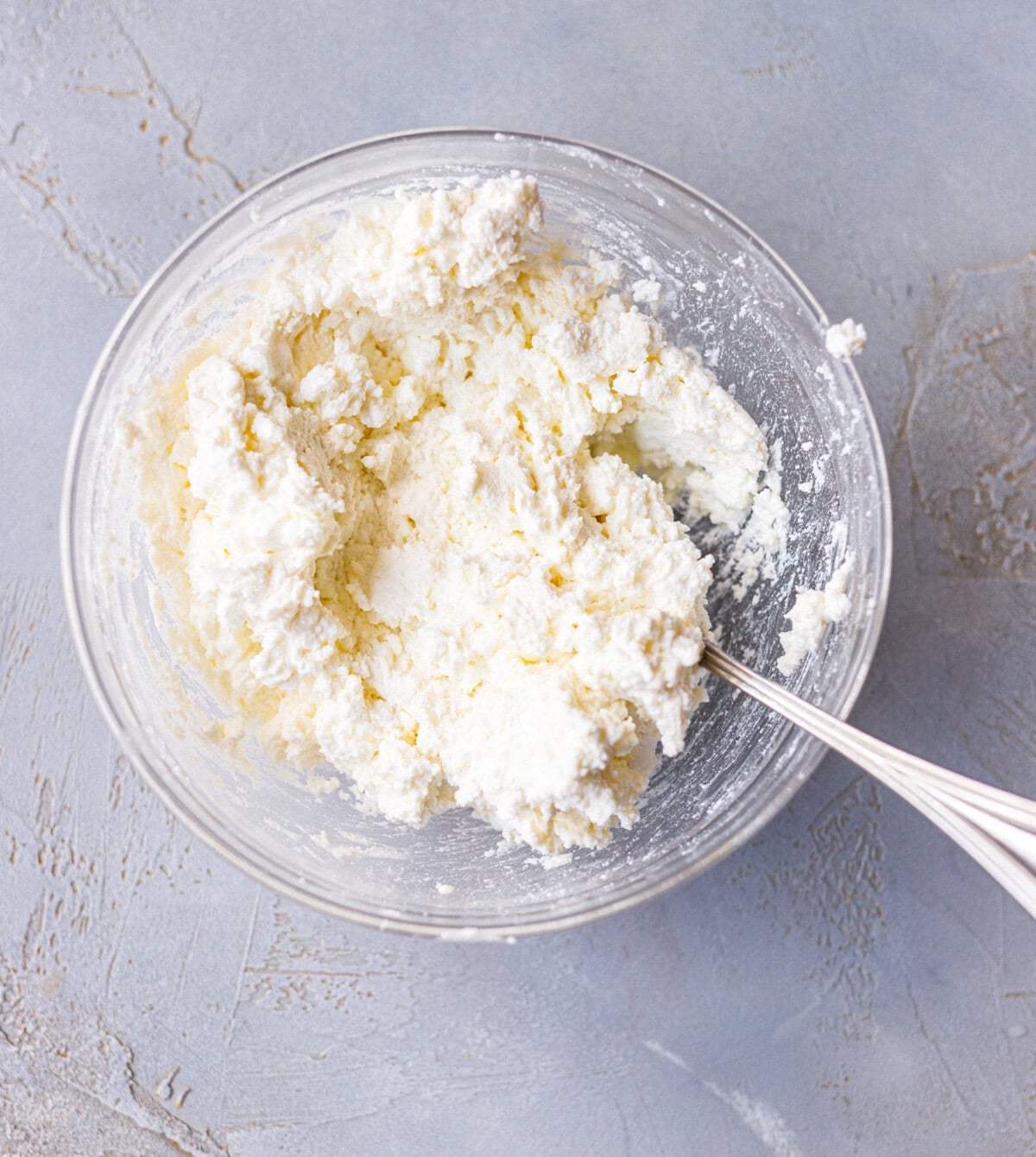 Crumbled feta and farmers cheese mixed together in a glass bowl for banitsa filling