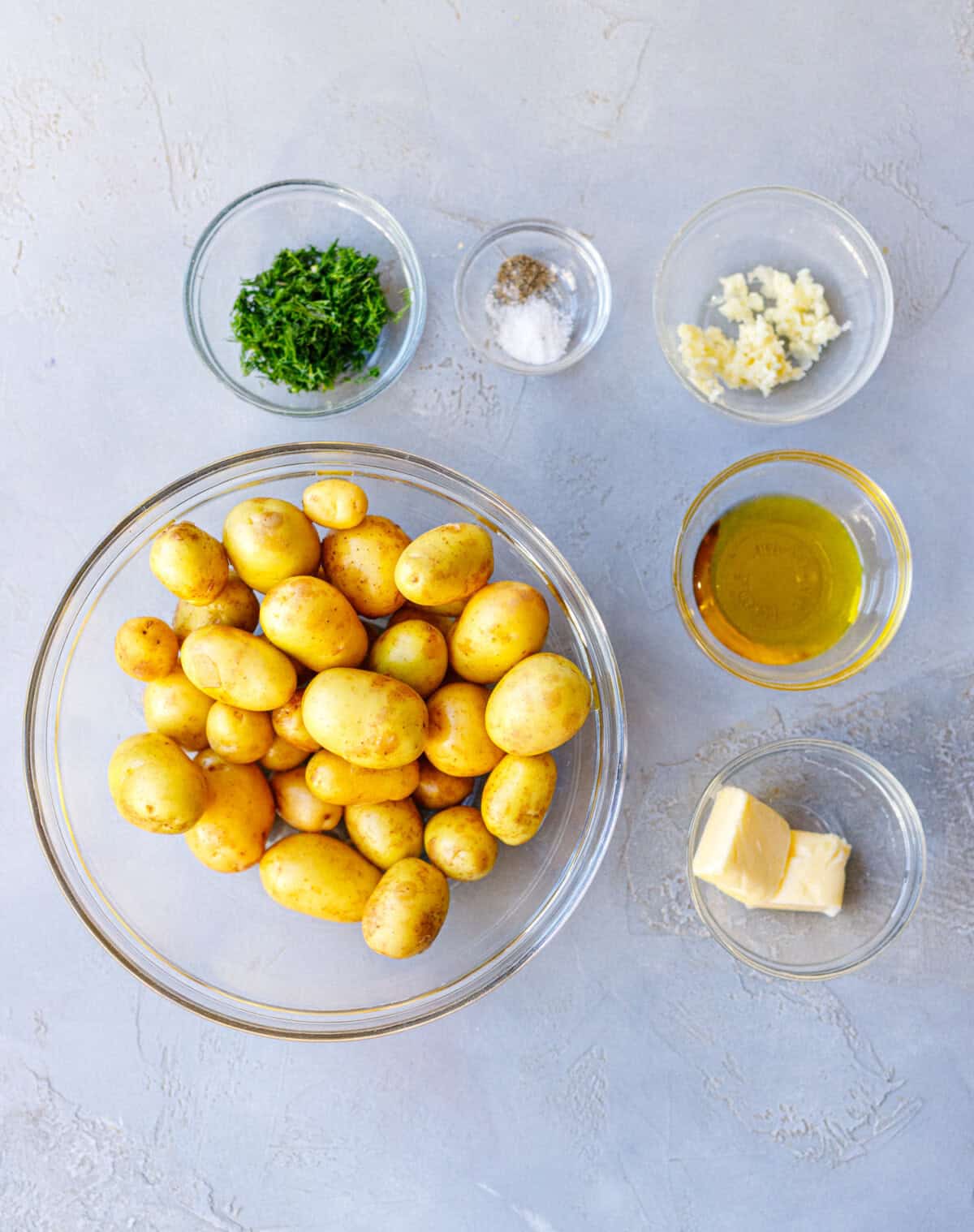 Ingredients for Bulgarian sautéed potatoes — new potatoes, fresh dill, garlic, olive oil, butter, salt, and pepper