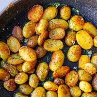 Close-up of golden Bulgarian sautéed potatoes with dill and garlic in a skillet
