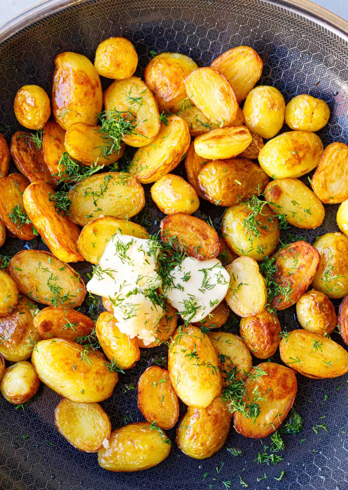 Adding butter, garlic, and fresh dill to sautéed potatoes off the heat