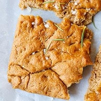 Close-up of spelt flour focaccia squares topped with rosemary sprigs and sea salt
