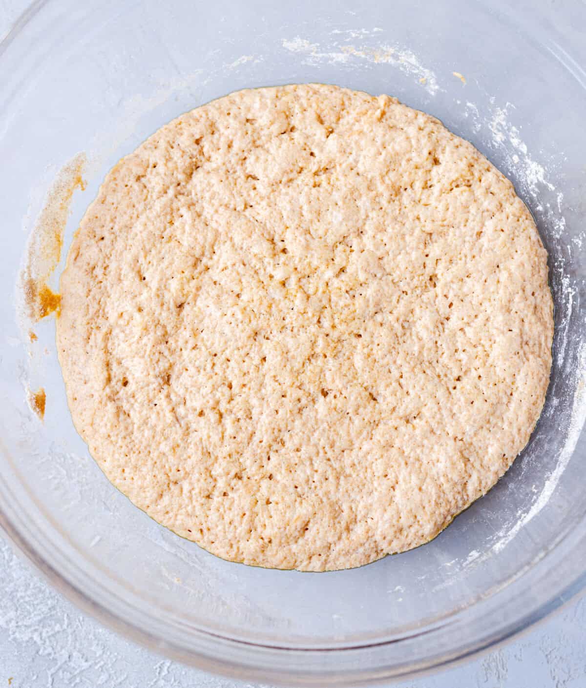 Spelt focaccia dough risen and doubled in a glass mixing bowl