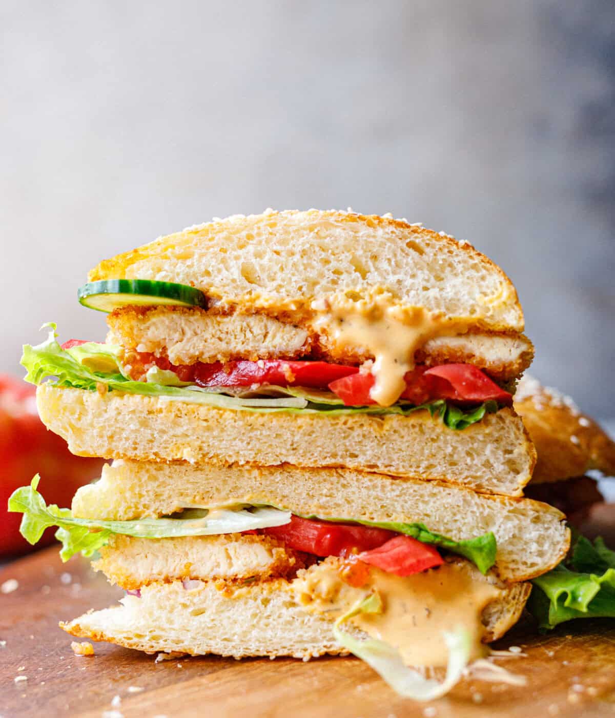 Crispy chicken burger cut in half showing juicy chicken and dripping sauce