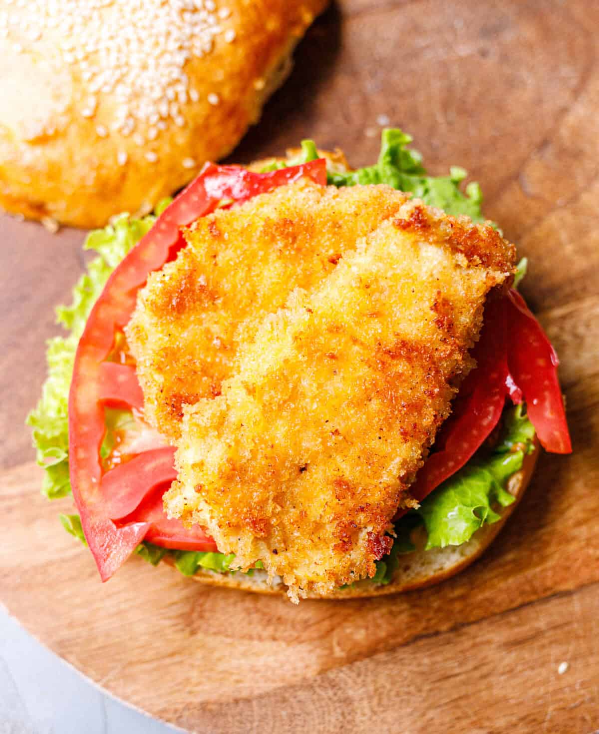 Golden panko-breaded chicken cutlet on lettuce and tomato on a sesame brioche bun