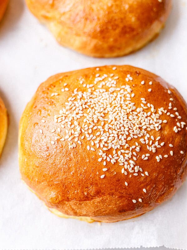 Golden brioche burger bun topped with sesame seeds on parchment paper