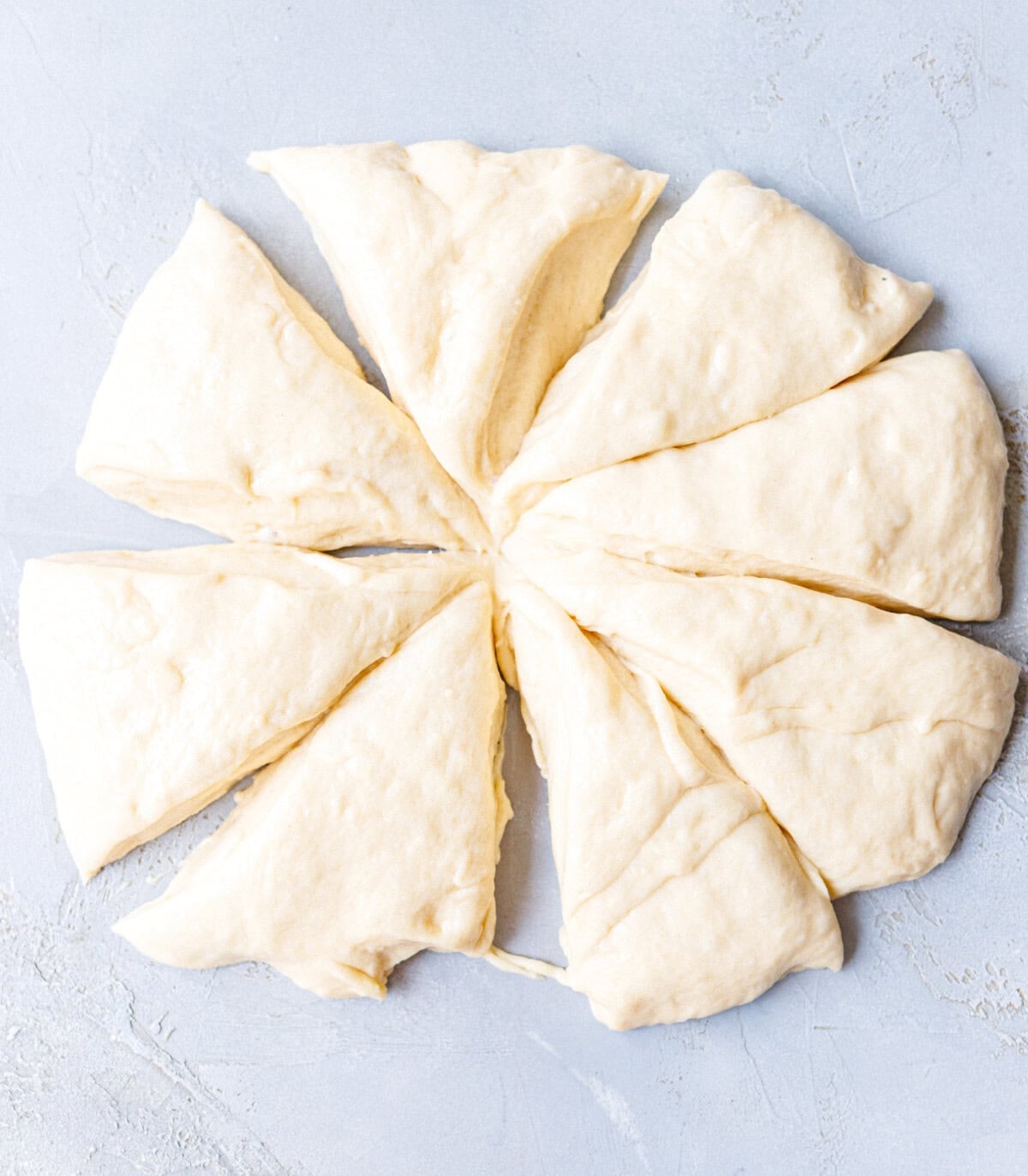 Brioche bread dough divided into eight equal wedges on a work surface