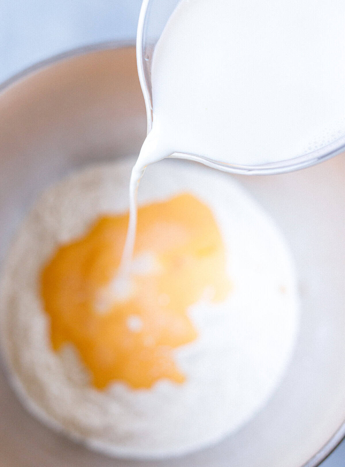 Pouring milk into flour, sugar, and eggs for brioche bun dough