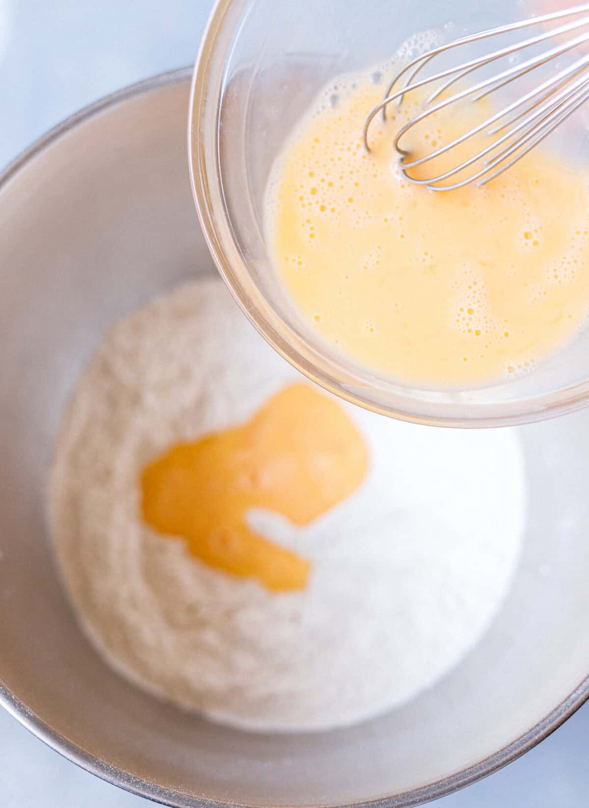 Whisked eggs poured into the dry ingredients for homemade brioche buns