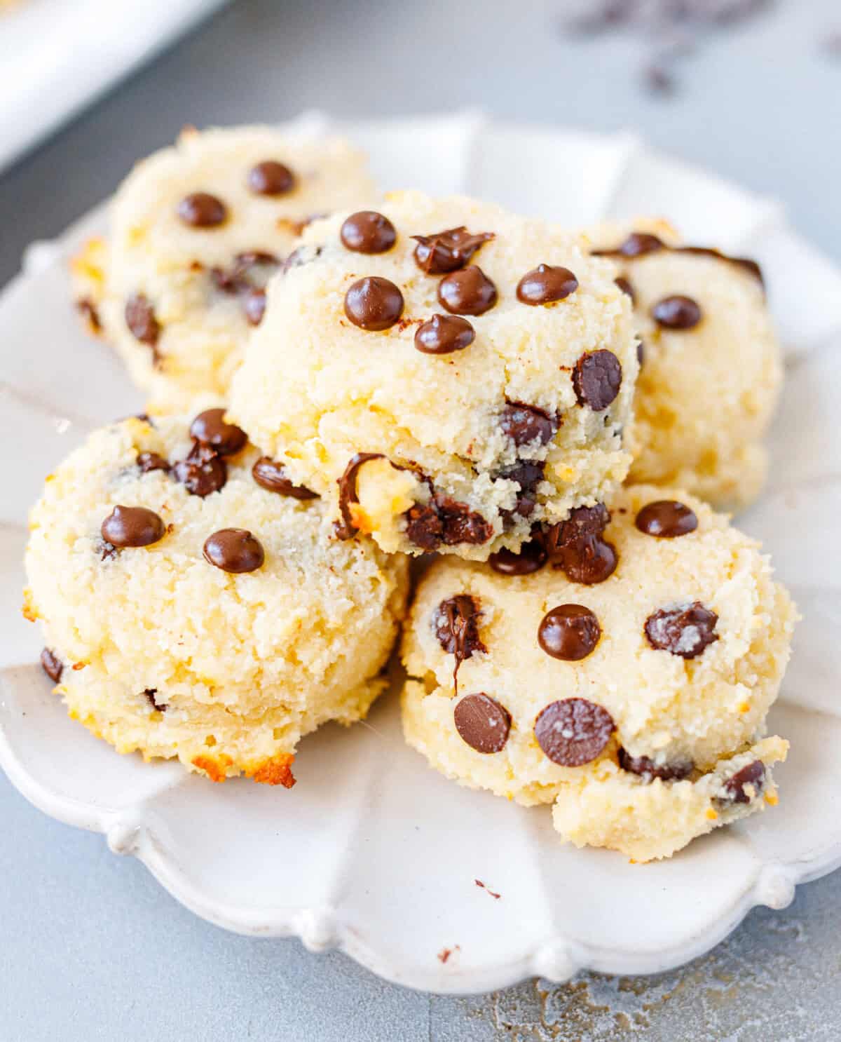 Soft chocolate chip cottage cheese cookies stacked on a white scalloped plate