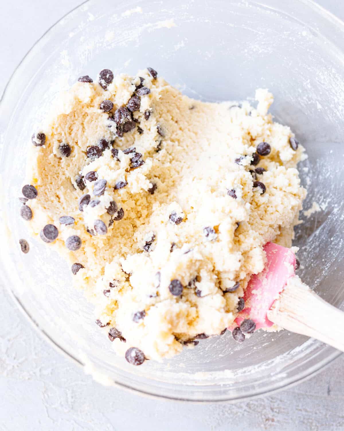 Cottage cheese cookie dough with chocolate chips folded in, in a glass bowl