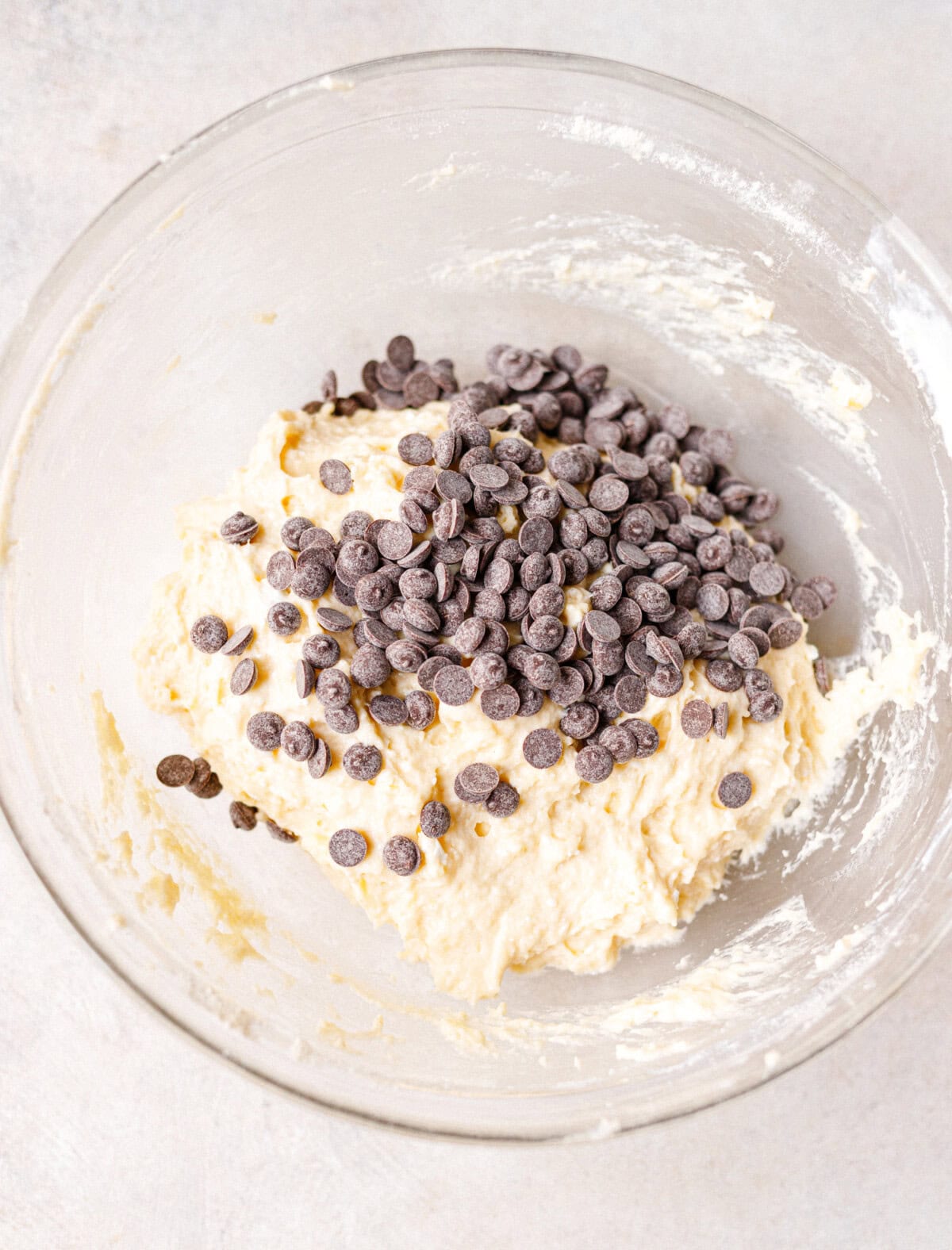 Chocolate chips being added to cottage cheese scone dough in a glass bowl