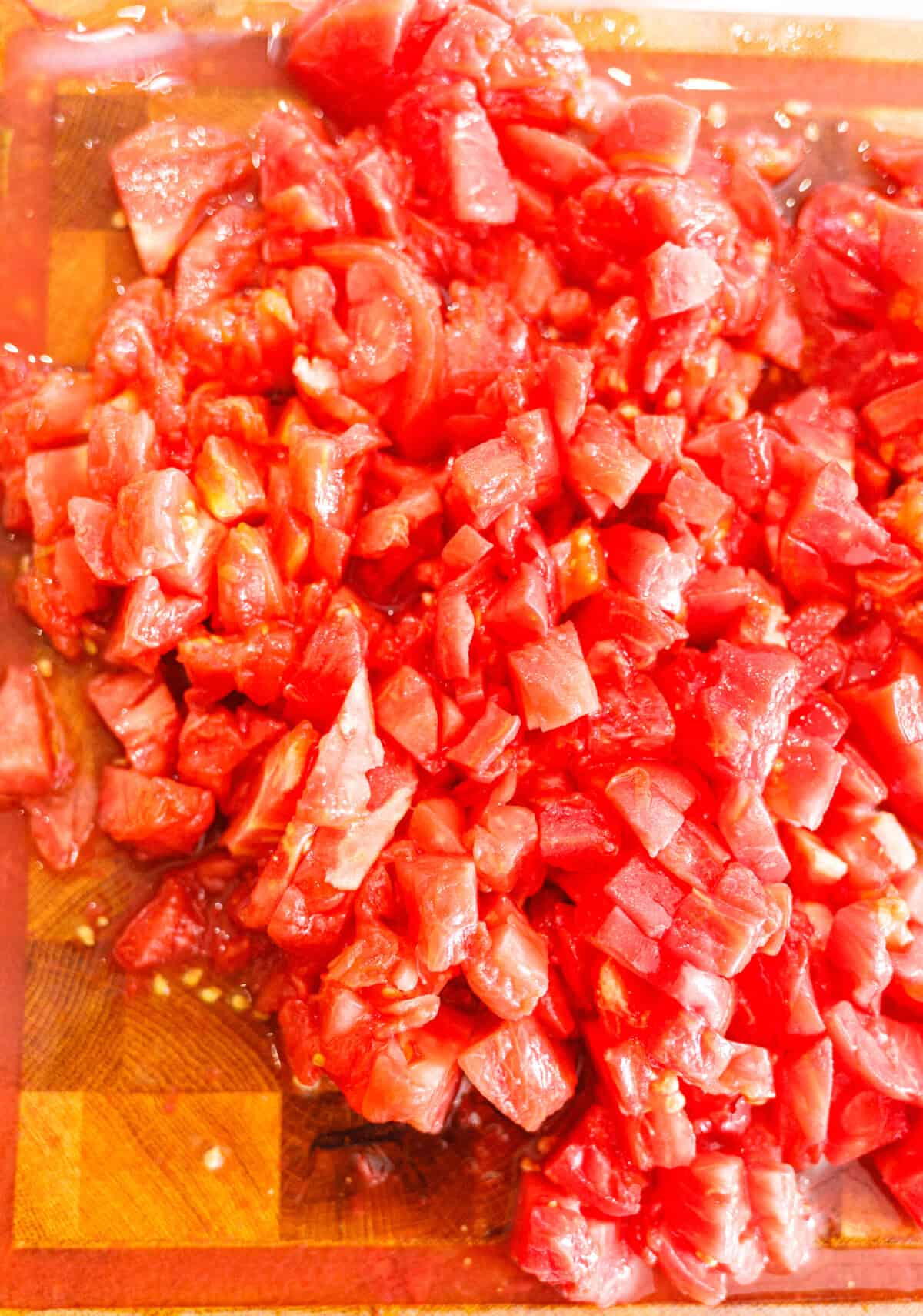 Peeled tomatoes chopped into small pieces on a cutting board