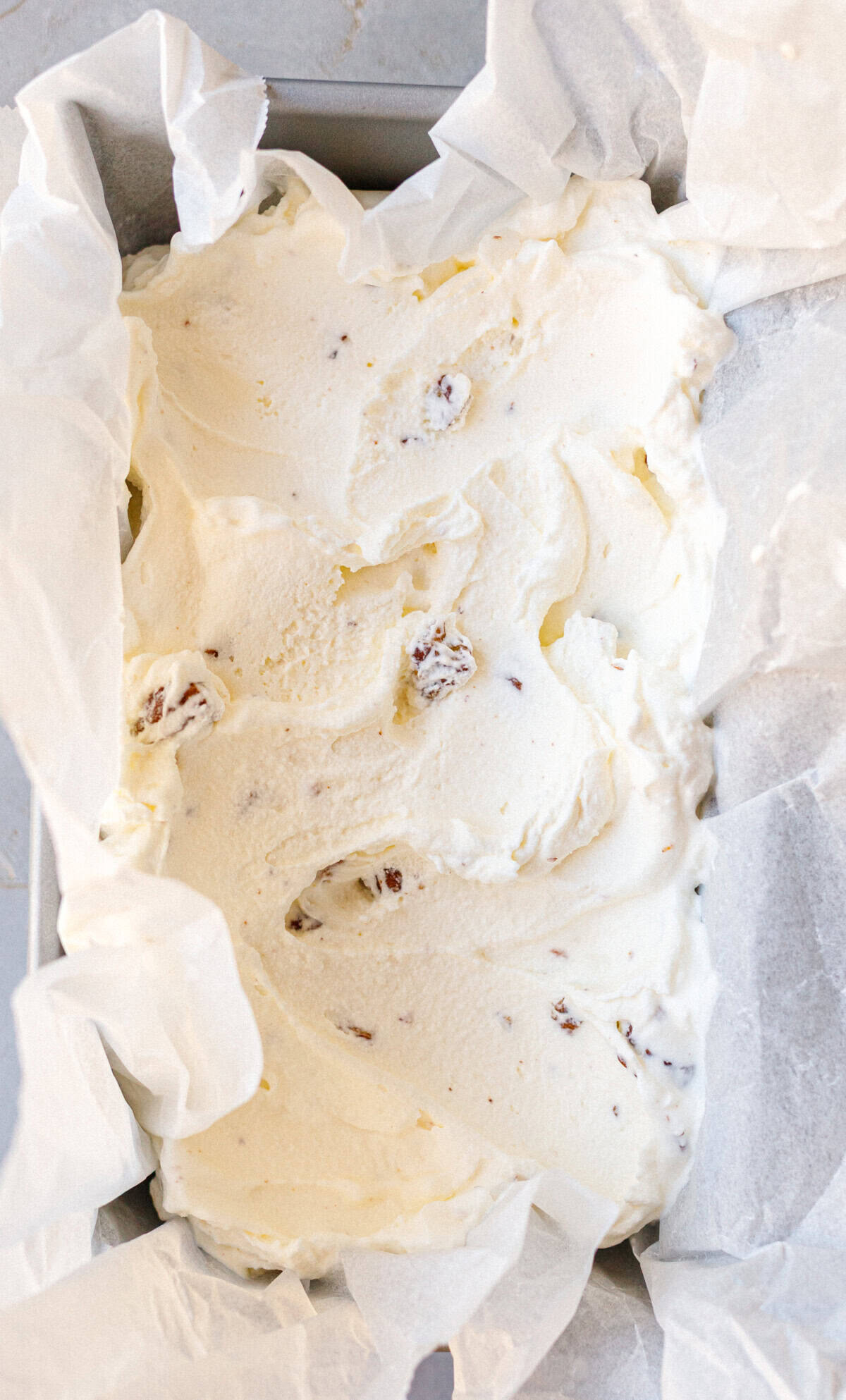Homemade butter pecan ice cream in a parchment-lined loaf pan ready to freeze.