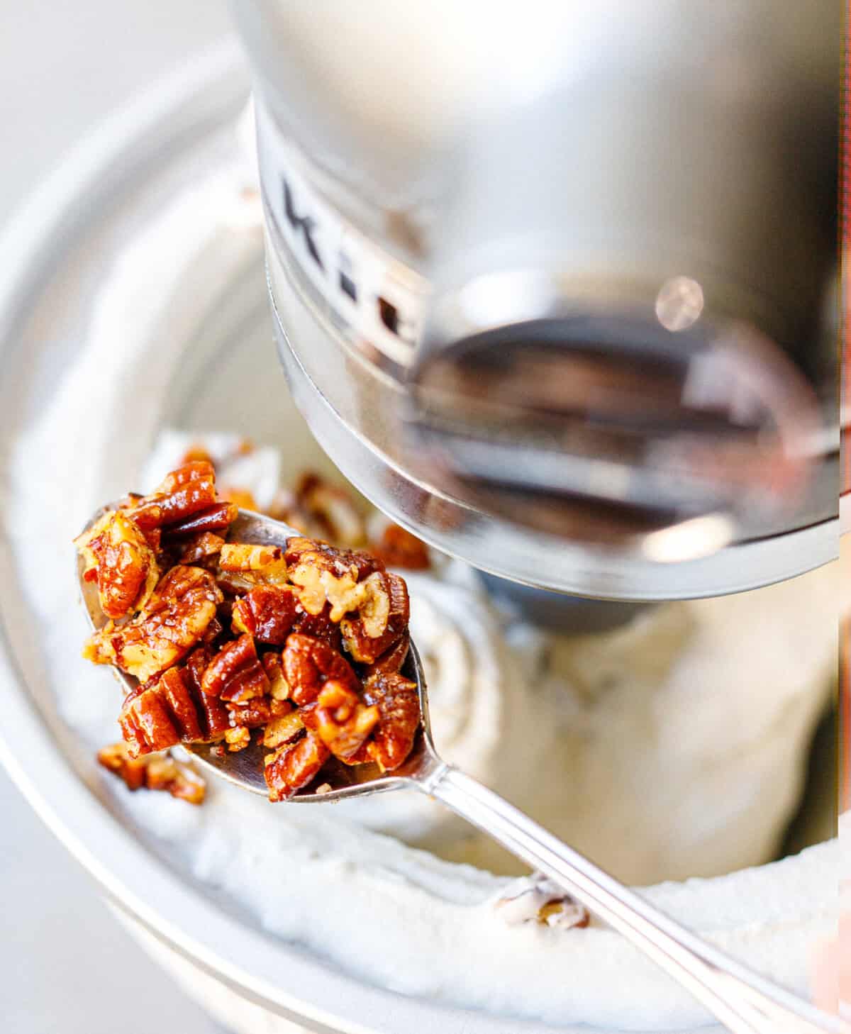Adding toasted pecans to churned butter pecan ice cream.