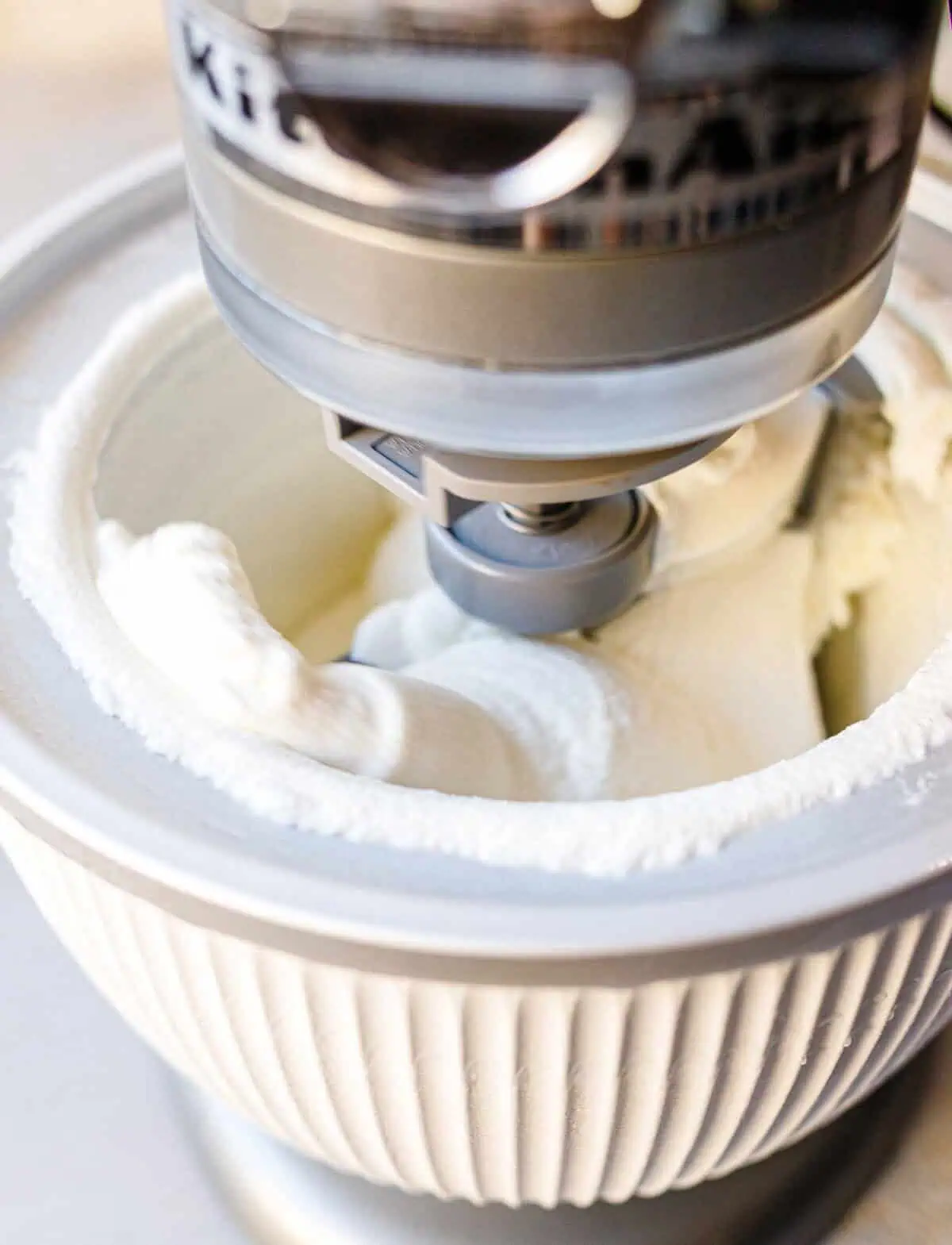 Butter pecan ice cream churning in a KitchenAid ice cream maker attachment.