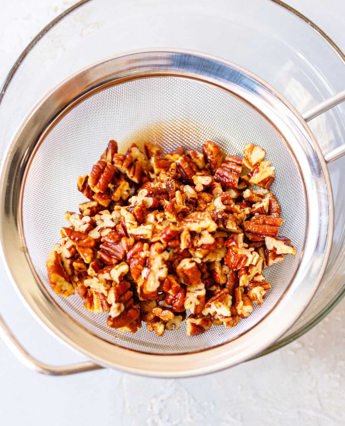 Toasted butter pecans draining before adding them to homemade ice cream.