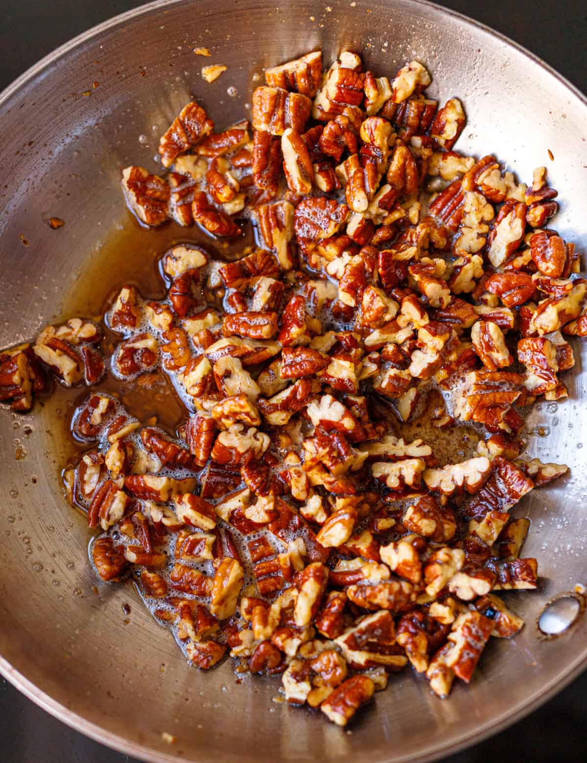 Chopped pecans cooking in butter and sweetener for toasted pecan ice cream.