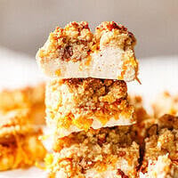 Three sugar-free pumpkin bars stacked high, with the top bar showing a thick white skyr layer under a golden crumb topping