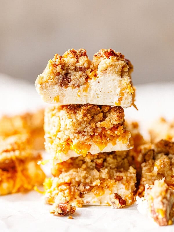Three sugar-free pumpkin bars stacked high, with the top bar showing a thick white skyr layer under a golden crumb topping