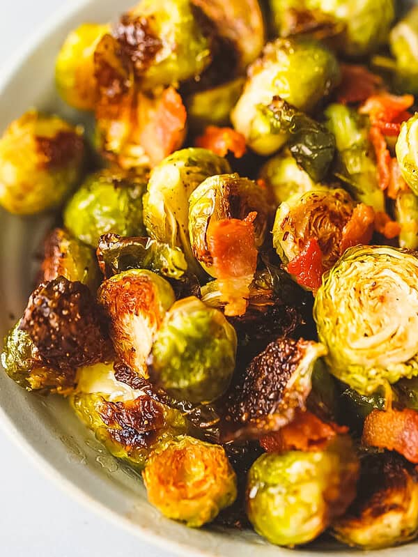 Close-up of crispy roasted Brussels sprouts with caramelized cut sides and chopped bacon.