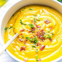 A bowl filled with creamy sweet potato soup. Made with sweet potatoes cooked in the microwave. Topped with bacon bits and parsley.