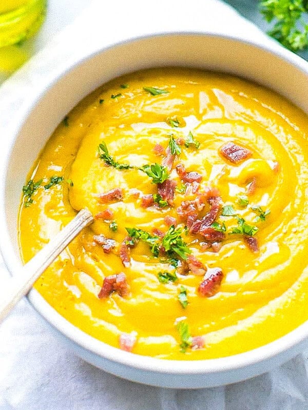A bowl filled with creamy sweet potato soup. Made with sweet potatoes cooked in the microwave. Topped with bacon bits and parsley.